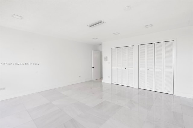 unfurnished bedroom featuring baseboards and multiple closets