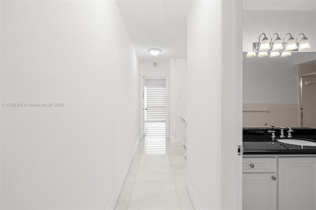 hallway with light tile patterned floors, baseboards, and a sink