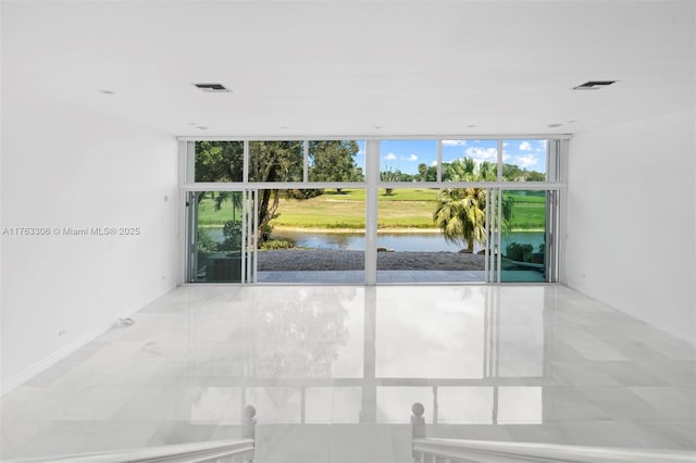 spare room with visible vents, a water view, and floor to ceiling windows