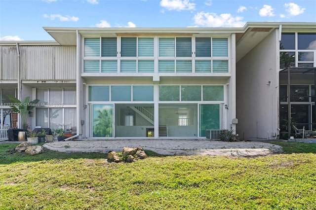 rear view of house featuring a lawn and stucco siding