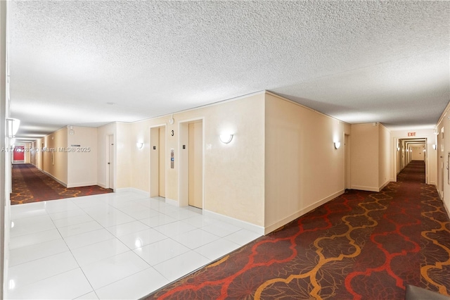 hallway featuring elevator, tile patterned flooring, and a textured ceiling