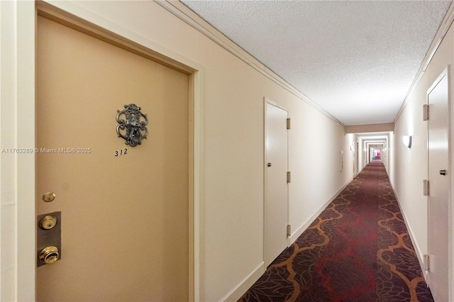 hall with baseboards, a textured ceiling, and ornamental molding