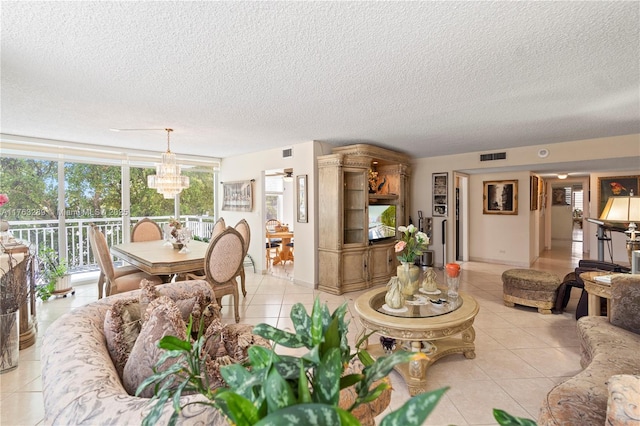 living room with visible vents, baseboards, light tile patterned floors, an inviting chandelier, and a textured ceiling