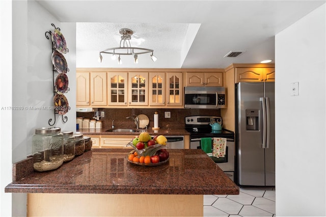 kitchen with visible vents, a peninsula, a sink, glass insert cabinets, and appliances with stainless steel finishes