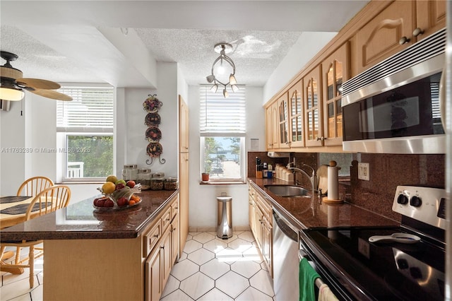 kitchen featuring a wealth of natural light, decorative backsplash, appliances with stainless steel finishes, a textured ceiling, and a sink