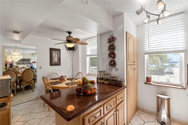 kitchen featuring visible vents, light tile patterned floors, ceiling fan with notable chandelier, rail lighting, and a textured ceiling