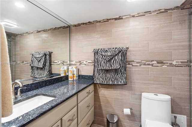 bathroom featuring toilet, vanity, and tile walls