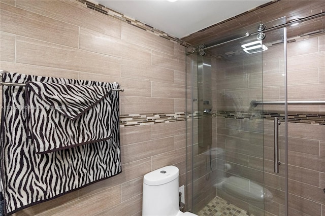 bathroom with a shower stall, toilet, and tile walls