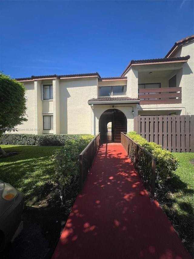 exterior space with stucco siding, fence, and a tiled roof