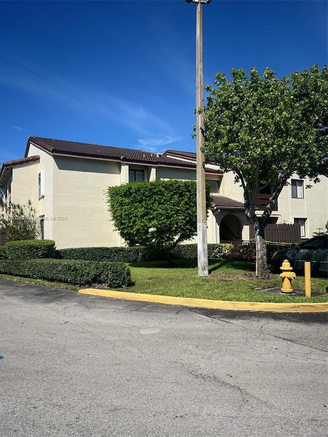 view of side of property with a tile roof and stucco siding