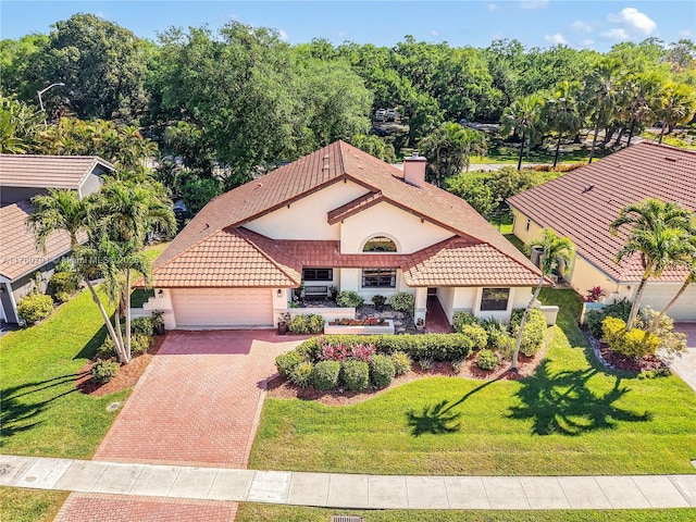 view of front of property with an attached garage, stucco siding, a front lawn, a tile roof, and decorative driveway