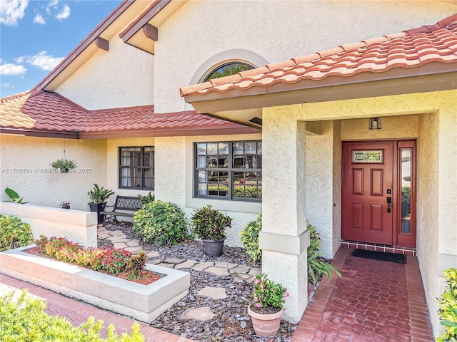 property entrance featuring a tiled roof, covered porch, and stucco siding