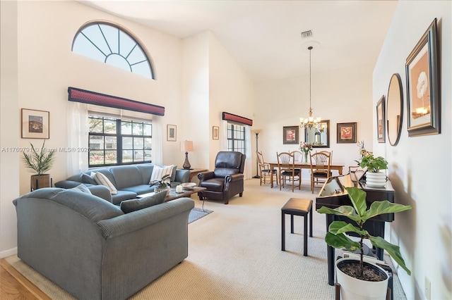 carpeted living room with a notable chandelier, visible vents, and a towering ceiling