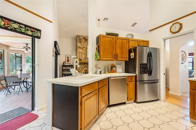 kitchen with a peninsula, ceiling fan, a sink, light countertops, and appliances with stainless steel finishes