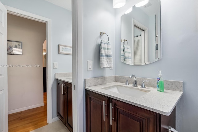 bathroom with baseboards, wood finished floors, and vanity