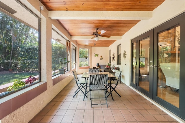 sunroom / solarium with beamed ceiling, wooden ceiling, a ceiling fan, and french doors