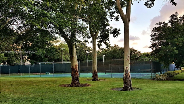 view of sport court with a lawn and fence