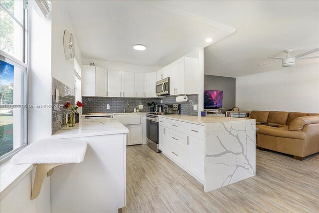 1 Keswick A 1, Deerfield Beach, FL 33442 - kitchen with stainless steel appliances, open floor plan, light stone counters, backsplash, and a peninsula