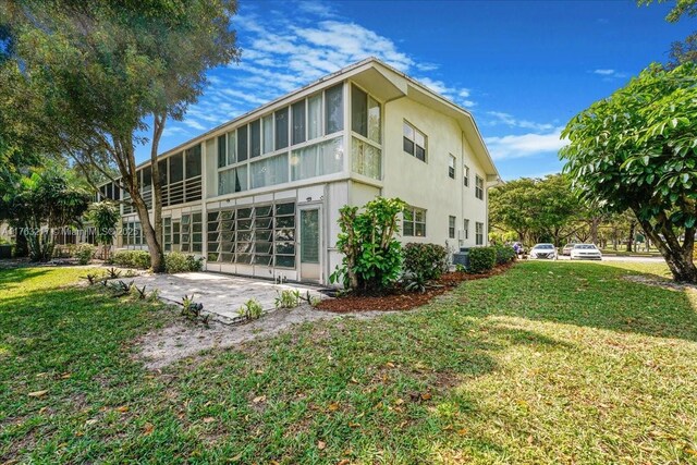1 Keswick A 1, Deerfield Beach, FL 33442 - rear view of property with stucco siding, a lawn, a garage, and central air condition unit