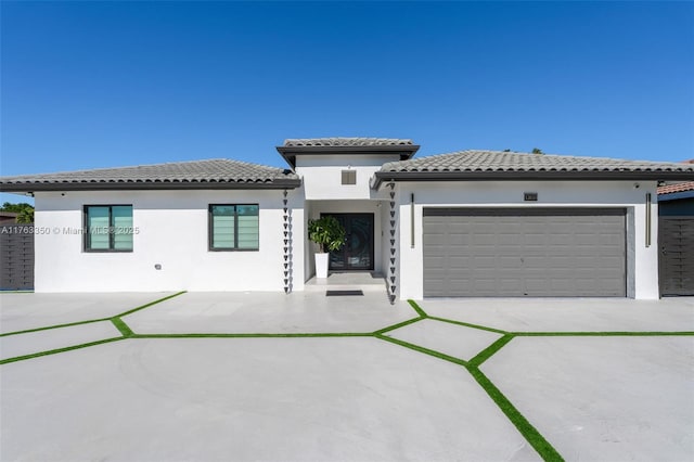 prairie-style home featuring concrete driveway, a garage, stucco siding, and a tiled roof