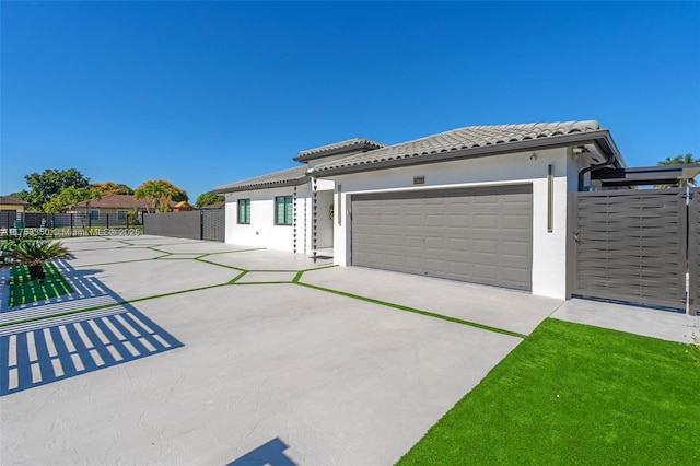 exterior space with a tile roof, an attached garage, driveway, stucco siding, and fence