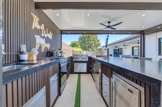 view of patio / terrace with ceiling fan, exterior kitchen, outdoor wet bar, grilling area, and fence