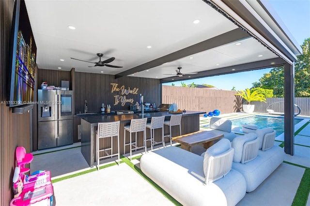 view of patio / terrace with fence private yard, a sink, ceiling fan, and outdoor wet bar