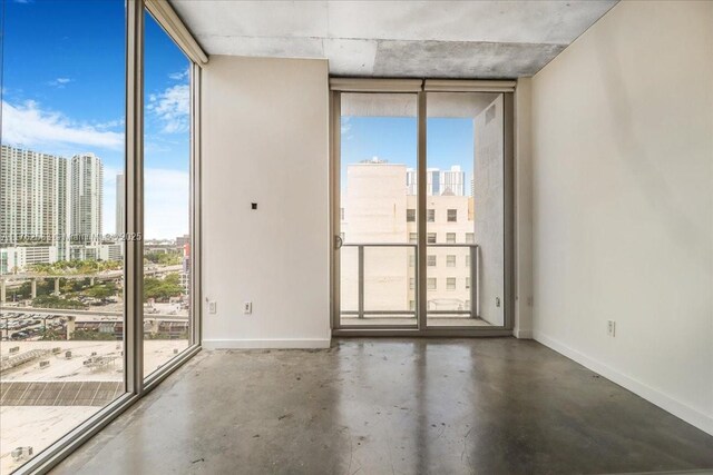 151 SE 1st St Unit 1011, Miami, FL 33131 - spare room with floor to ceiling windows, a skyline view, concrete flooring, and baseboards