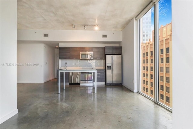 151 SE 1st St Unit 1011, Miami, FL 33131 - kitchen featuring stainless steel appliances, baseboards, finished concrete floors, light countertops, and a breakfast bar area