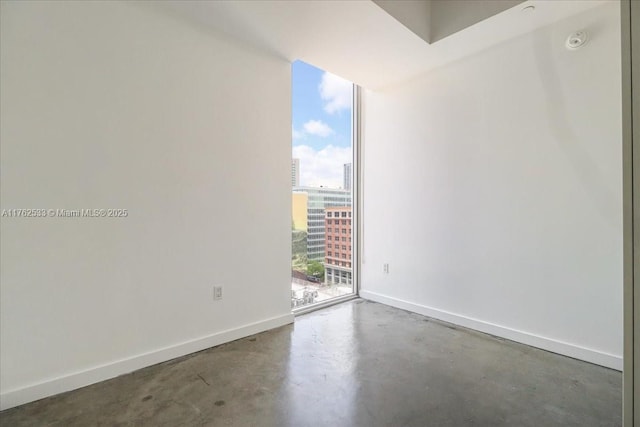 151 SE 1st St Unit 1011, Miami, FL 33131 - spare room featuring concrete flooring, a view of city, baseboards, floor to ceiling windows, and a smoke detector