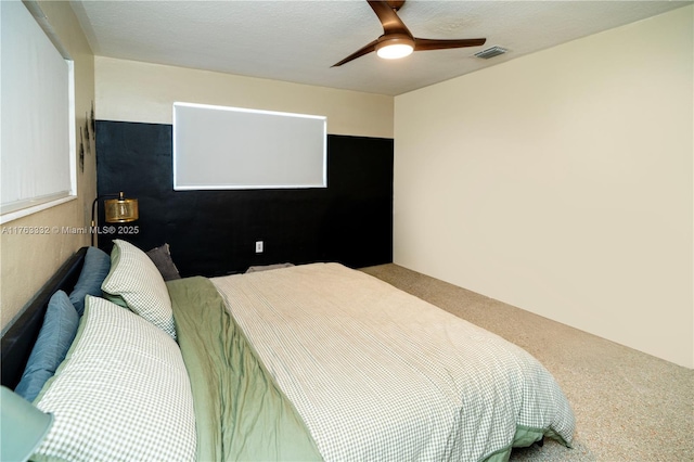 carpeted bedroom featuring a ceiling fan, visible vents, and a textured ceiling