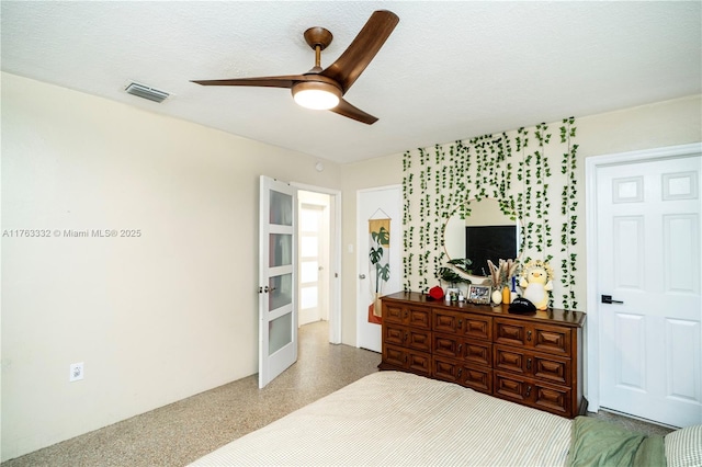 bedroom with visible vents, a textured ceiling, french doors, speckled floor, and ceiling fan