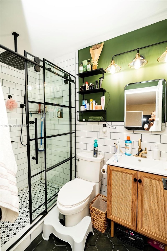 bathroom with tile patterned floors, toilet, tile walls, a shower stall, and vanity