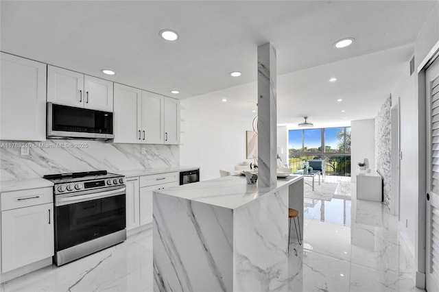 kitchen with recessed lighting, light stone counters, white cabinets, tasteful backsplash, and appliances with stainless steel finishes