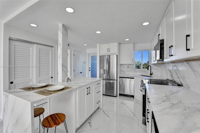 kitchen featuring light stone countertops, marble finish floor, appliances with stainless steel finishes, and white cabinetry