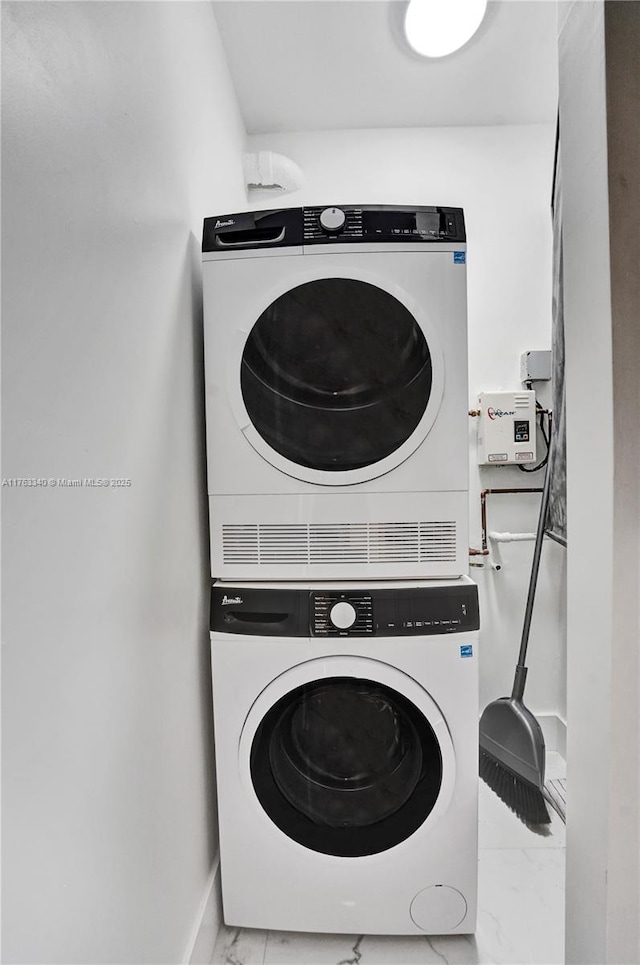 laundry room featuring laundry area, marble finish floor, baseboards, and stacked washer / drying machine