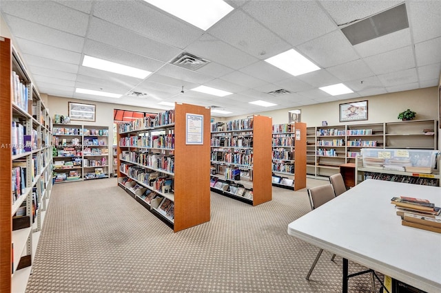 carpeted office featuring bookshelves, visible vents, and a drop ceiling