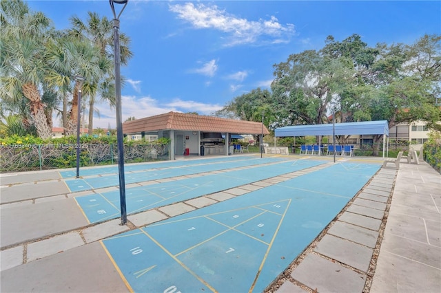 view of property's community with shuffleboard and fence