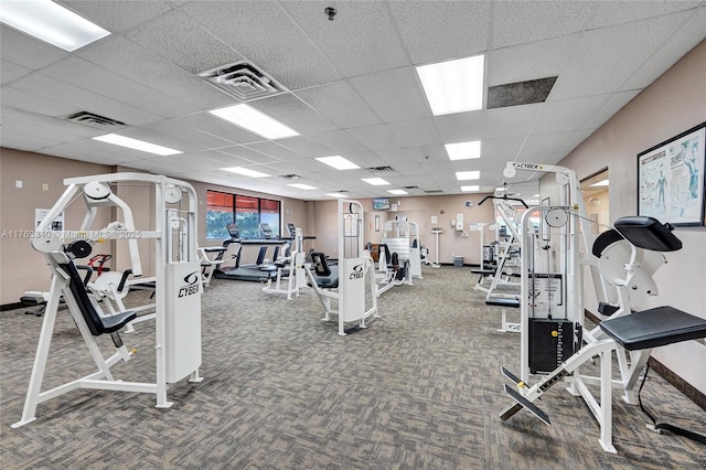 gym featuring a paneled ceiling, carpet flooring, and baseboards
