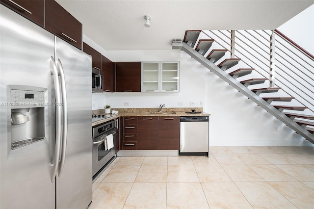 41 SE 5th St Unit 1815, Miami, FL 33131 - kitchen featuring stainless steel appliances, a sink, glass insert cabinets, light stone countertops, and dark brown cabinets