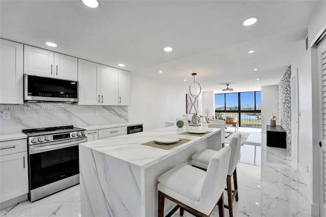 kitchen featuring recessed lighting, white cabinets, appliances with stainless steel finishes, tasteful backsplash, and a center island