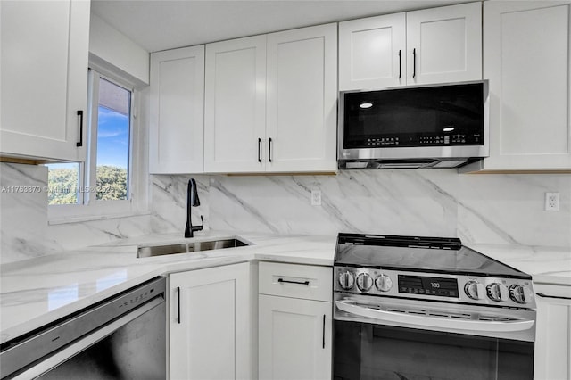 kitchen featuring a sink, light stone counters, tasteful backsplash, stainless steel appliances, and white cabinets