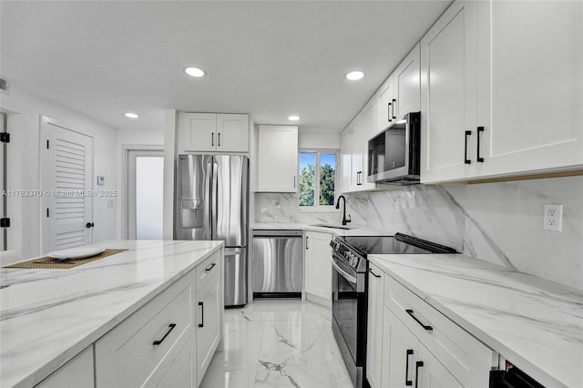 kitchen featuring white cabinetry, a sink, light stone countertops, and stainless steel appliances