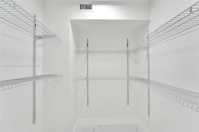 walk in closet with visible vents and marble finish floor