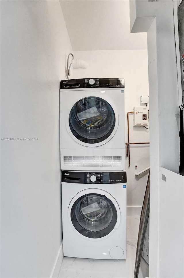 clothes washing area with laundry area, marble finish floor, baseboards, and stacked washer and dryer