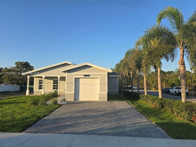 ranch-style house featuring a front lawn, decorative driveway, and a garage