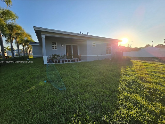 rear view of property with a yard and stucco siding