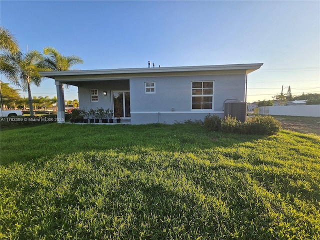 back of property featuring stucco siding, a lawn, and central AC unit