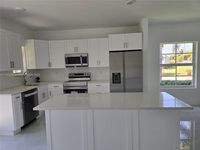 kitchen with a sink, a kitchen island, white cabinetry, and stainless steel appliances