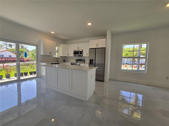 kitchen featuring white cabinetry, a kitchen island, appliances with stainless steel finishes, and light countertops